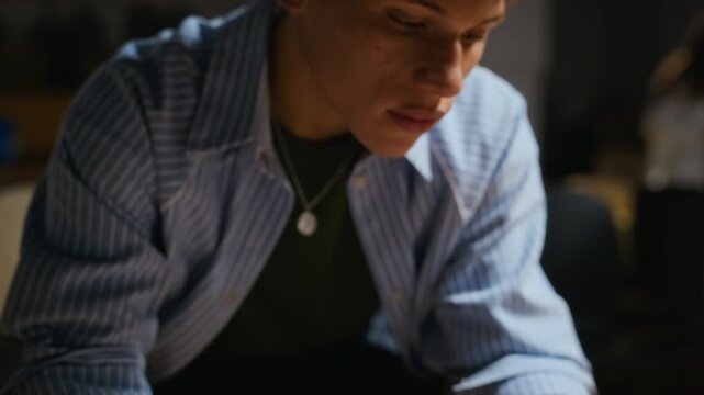 African American young adult male actor reading theater script during rehearsal as camera tilts up to face. Footage fits drama education campaigns or creative arts promotional videos