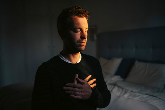 Man with hands on chest practicing breathing exercises at home