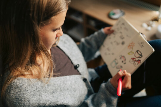 High angle view of girl drawing doodles in notebook at home