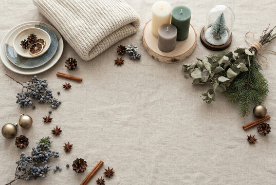 Cozy winter holiday flat lay composition with candles, pine cones, and greenery.