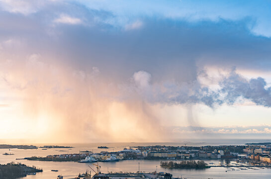 Aerial view of the Helsinki coastline and harbor islands under dramatic rain clouds during golden hour in Helsinki, Uusimaa, Finland.