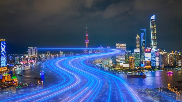 Aerial view of the Shanghai skyline at night featuring the Oriental Pearl Tower and Shanghai Tower illuminated with vibrant blue light trails over the Huangpu River in Shanghai, Shanghai, China.