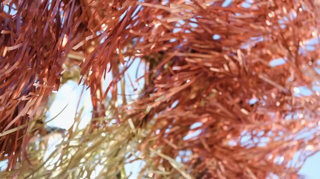 Close-up of metallic copper and gold colored decorative tinsel fluttering in the wind outdoors