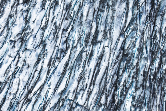 Aerial view of the glacial ice at Fjallsarlon, showcasing deep crevasses and intricate textures of blue and white ice in Sveitarfelagid Hornafjordur, Iceland.