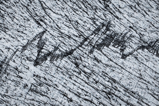 Aerial view of Fjallsarlon glacier surface showing intricate ice textures, deep crevasses, and dark volcanic ash deposits in Sveitarfelagid Hornaf, Iceland.