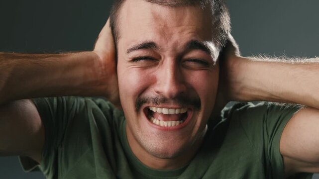 Young Man Covering His Ears In Distress In Close Up