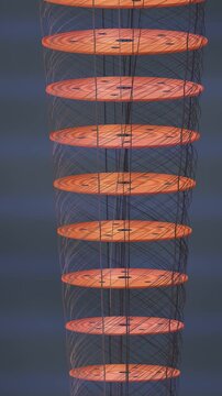 Rotating Gold Plate Stack of a Quantum Computer Dilution Refrigerator With Spiraling Coaxial Cables, Seamless Loop in rich orange tones vertical 9:16