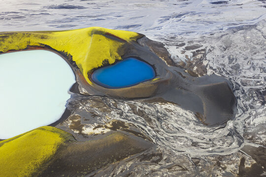 Aerial view of vibrant green moss-covered volcanic hills and striking blue crater lakes in the highlands of Iceland.