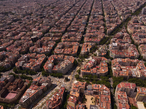 Aerial view of the Eixample district with its iconic grid layout, octagonal city blocks, and terracotta rooftops under a clear sky in Barcelona, Catalonia, Spain.