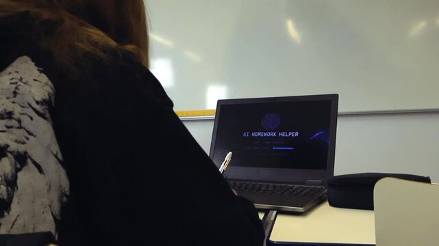 Over the shoulder view of a female student using a laptop with an artificial intelligence homework helper program in a classroom, representing modern education and technology in learning