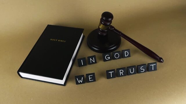 Conceptual scene with the Holy Bible, a judge's wooden gavel, and the American motto In God We Trust, symbolizing the intersection of religious faith, law, justice, and national values