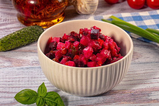 Bowl of vibrant beet salad with cucumber, basil, and olive oil on rustic wood