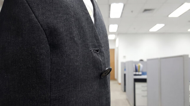 Loose hanging suit button dangling on single thread in office