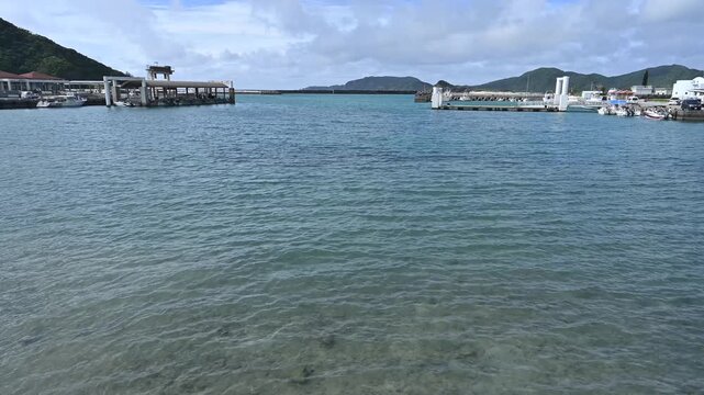 沖縄・座間味島の港から望む透明なエメラルドブルーの海と港町、慶良間諸島の離島風景【沖縄・座間味島風景動画】