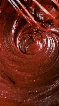 melted chocolate being whisked in swirling spiral texture, close-up- vertical video