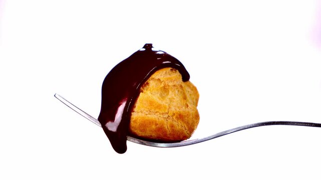 chocolate-covered cream puff pastry on fork, white background