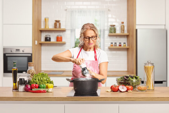 Mature woman cooking and seasoining food