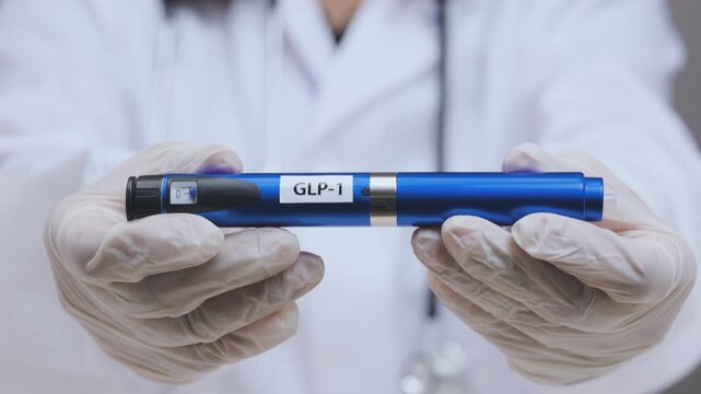 Gloved hand of doctor holding modern medical weight loss injection pen device for effective healthcare treatment in clinic room