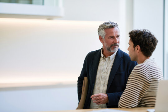 Two professionals engaged in a conversation in a contemporary office space, emphasizing the importance of collaboration and innovation in the business world.