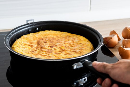 Spanish potato omelette cooking in frying pan