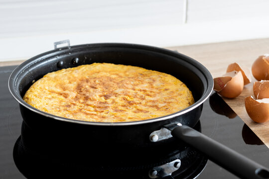 Spanish potato omelette cooking in frying pan