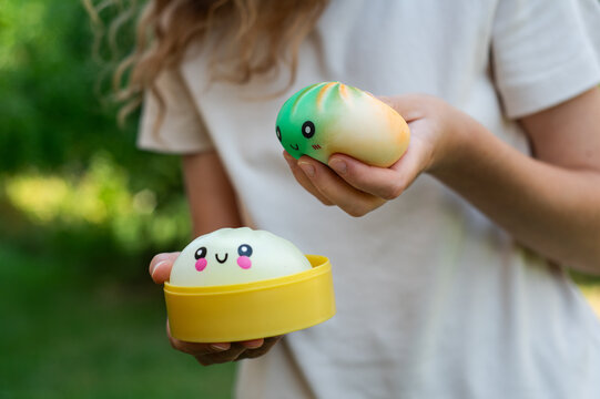 Girl squeezing cute dumpling squishy stress toys in garden