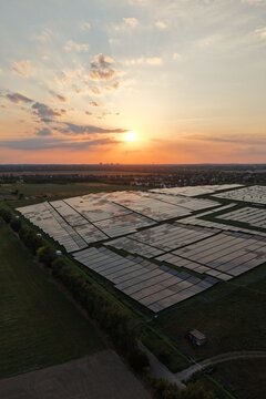 Aerial view of SkyPoint Grosziethen solar farm at sunset with rows of photovoltaic panels in the rural landscape of Schonefeld, Brandenburg, Germany.