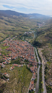 Aerial view of Cabezuela del Valle with its dense cluster of terracotta rooftops, winding river, and surrounding terraced hillsides in Cabezuela del Valle, Extremadura, Spain.