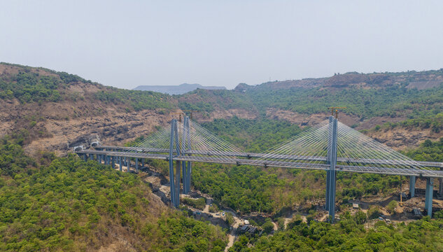 Aerial view of the Missing Link Suspension Bridge spanning a lush green valley with surrounding hills and tunnel entrances in Lonavala, Maharashtra, India.