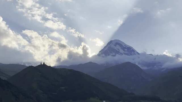 Scenic panoramic video of a lush green mountain valley and majestic peaks in the Caucasus mountains of Georgia, showcasing breathtaking natural landscapes, rolling hills, and dramatic cloudy skies.