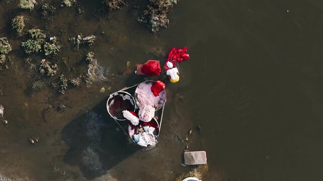 Aerial view of a traditional dhobi washer doing laundry by hand in the polluted waters of the yamuna river in india