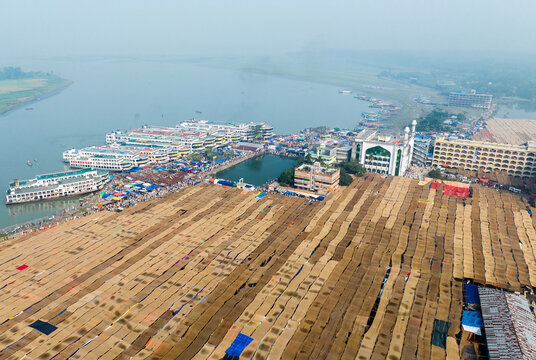 Aerial view of the expansive Charmonai Mahfil area featuring rows of temporary tent shelters, a mosque, and passenger boats docked along the riverbank in Charmonai, Barisal Division, Bangladesh.