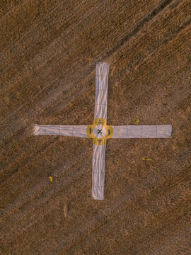 Aerial view of a large cross-shaped landing target marker placed in a dry harvested field in Gravina in Puglia, Apulia, Italy.