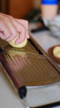Close up of hand slicing potato with mandoline slicer in kitchen video