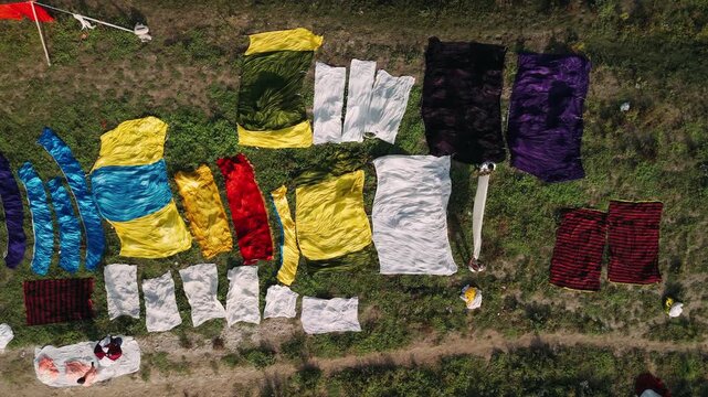 Aerial view of colorful textiles drying on a grassy riverbank in agra, india