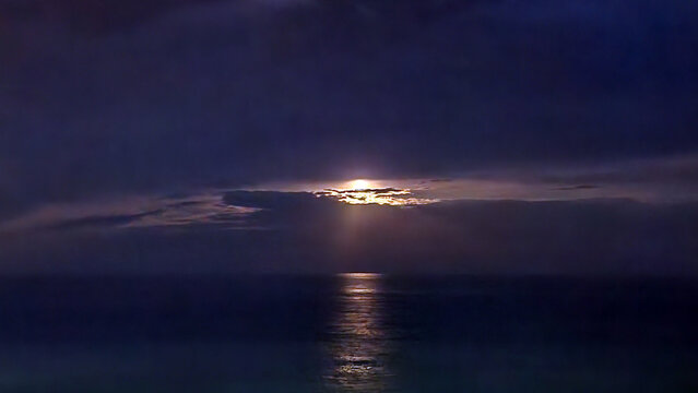Moonlight filtering through stratocumulus beneath an altostratus veil, creating a layered atmospheric scene over the calm Mediterranean Sea at night