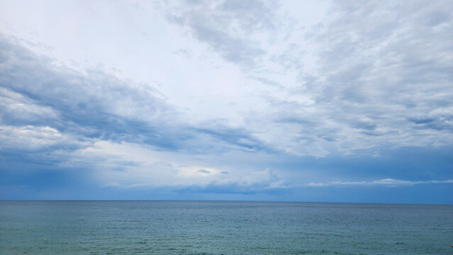 Altostratus and stratocumulus undulatus clouds covering the Mediterranean coast, with distant cumulus formations along the sea horizon