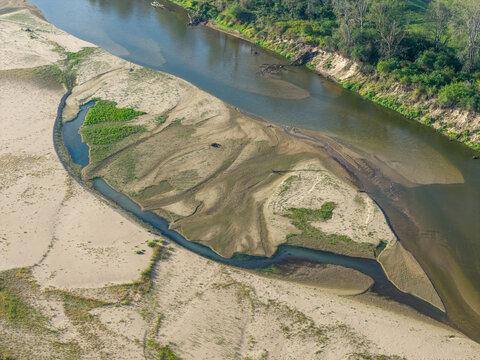 Aerial view of a very dry river bed with exposed sandbanks and patches of vegetation along the riverbank in Poland.