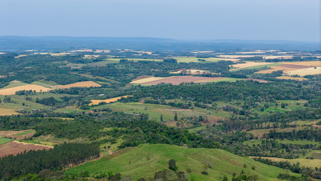 Aerial view of rolling hills and agricultural fields with patches of forest in the rural landscape of Nueva Alborada, Itapua Department, Paraguay.