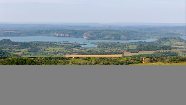 Aerial view of the Parana River winding through lush green hills and agricultural fields in Nueva Alborada, Itapua Department, Paraguay.