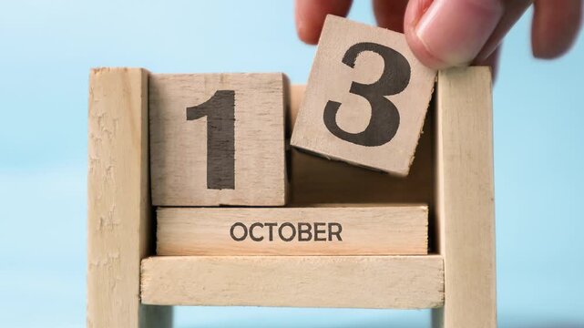 A woman&rsquo;s hand is holding a wooden block for October. Month of October wooden block calendar time-lapse.