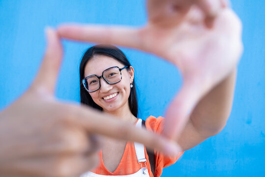 Happy young asian woman framing creative vision with hands