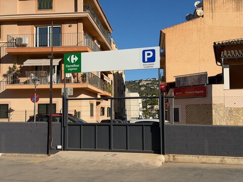 Mallorca, spain, august 30, 2026, carrefour express parking entrance with customer exclusive sign and metal gate in andratx, balearic islands, spain