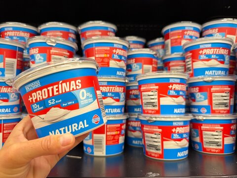 Mallorca, spain, august 30, 2026, hand holding hacendado plus proteinas yogurt in a supermarket aisle, healthy protein dairy product for fitness nutrition