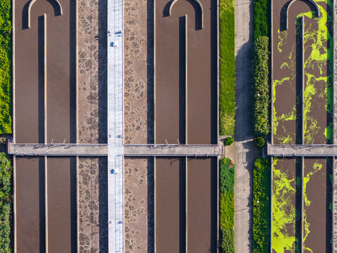 Aerial view of Wastewater Treatment Plant with aeration tanks, bubbling water, and green algae in Poznan, Greater Poland Voivod, Poland.