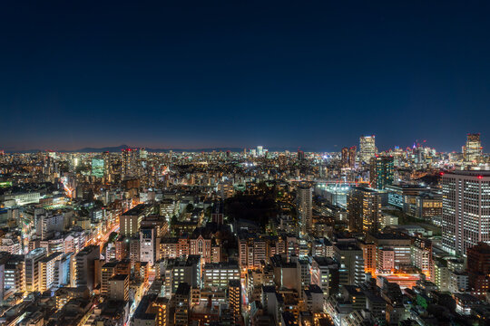Tokyo cityscape in Minato ward with Mount Fuji silhouette glowing against twilight sky