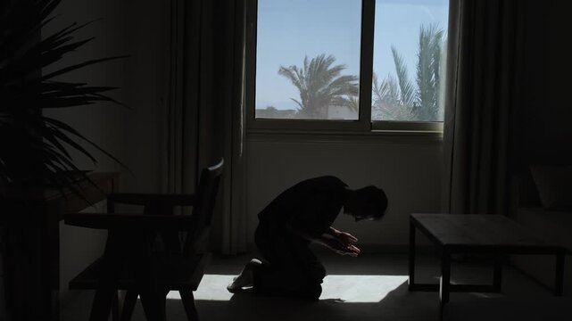 Man receives devastating news about loss of a loved one during a phone call and collapses in grief, dramatic silhouette and cinematic slow motion