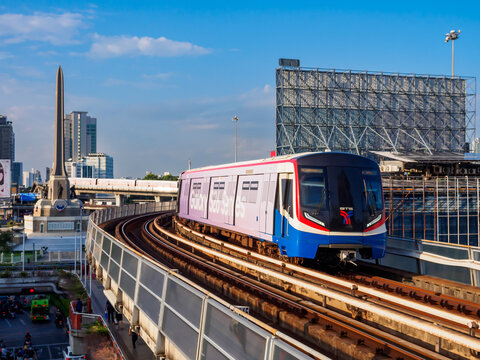 Bangkok, Thailand - July 8, 2026 : The BTS Skytrain runs in and out of Victory Monument Station in the afternoon, offering a beautiful view of the Victory Monument itself.