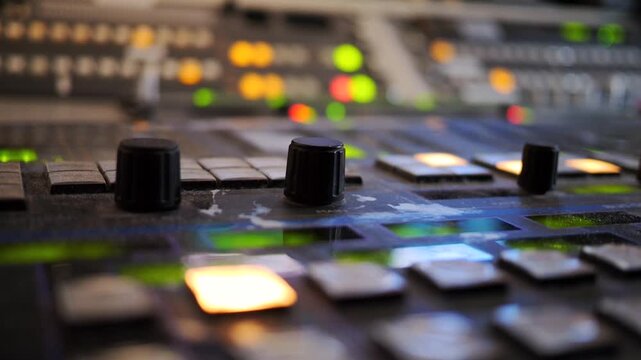 Close-up of a television operator adjusting controls on a professional broadcast console during studio production