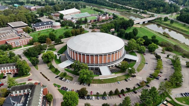 Drone footage of Ohio University in Athen, Ohio on a sunny day featuring the convocation center and many campus buildings.